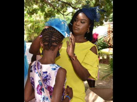 Children’s officer in the Mental Health Unit at the CPFSA, Sassah-Gaye McPherson, places a fascinator on a ward of the State during the CPFSA girls’ empowerment tea party held at Tropical Elegance on Saturday, June 18. 