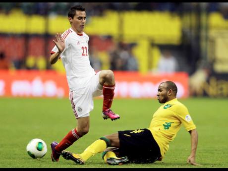 File photo shows Jamaica’s Rodolph Austin a he makes a typically uncompromising sliding challenge on Mexico’s Paul Nicolas Aguilar (left) during a World Cup 2014 qualifying football match at the Azteca stadium in Mexico City.