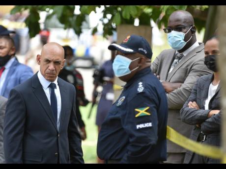 Commissioner of Police Major General Antony Anderson (left) and Deputy Commissioner Fitz Bailey (third left) look on intensely at the Clarendon crime scene where five persons were murdered.