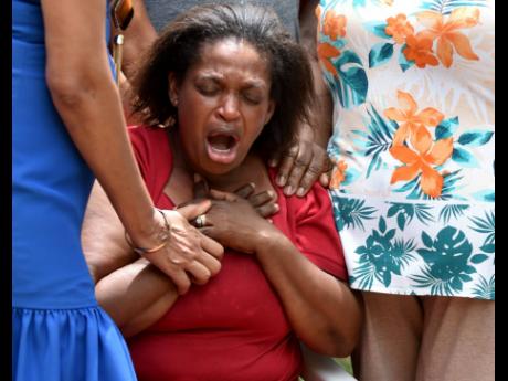 Gwendolyn Wright is comforted as she mourns the loss of her only daughter, 31-year-old Kemesha Wright, and her four children in Cocoa Piece, Clarendon, on Tuesday.