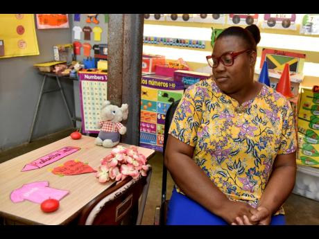Tamara Blair-Robinson, infant teacher at Beulah All-Age School, sits by a desk memorialising five-year-old Rafaella Smith and 12-year-old Sharalee Smith, mass murder victims. 