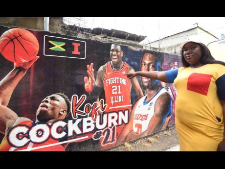 Lindiway Cockburn, sister of Kofi Cockburn, who was signed to the Utah Jazz during the NBA Draft on June 23, points to a mural in his honour in his home community of Common , which is located off Red Hills Road in St Andrew.