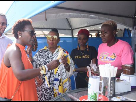 Grange and Opposition Spokesperson for Tourism Senator Janice Allen (left), visit the Fruit Blossoms booth at the 2022 Jamaica Rum Festival held at The Aqueduct in Montego Bay on Saturday. 