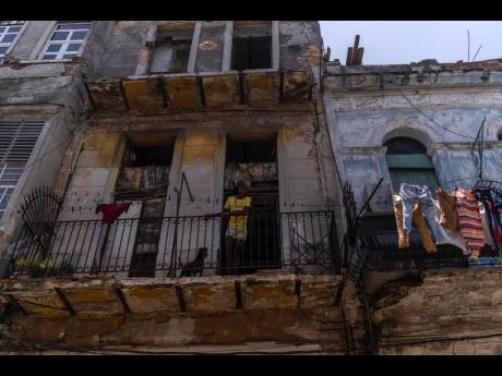 
Anet Ayala and her dog peer from her balcony in Havana, Cuba, Monday, June 13, 2022.