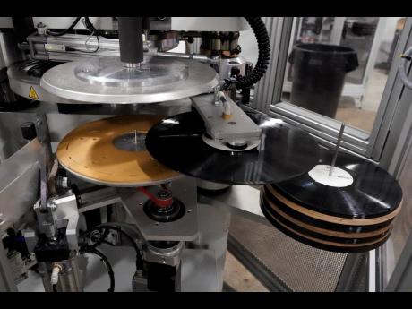 Freshly pressed vinyl records are produced in a stamper.