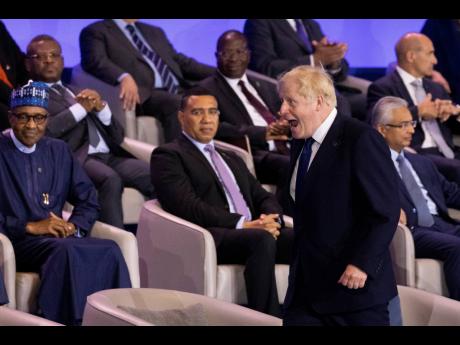 Jamaican Prime Minister Andrew Holness (centre) looks on as British Prime Minister Boris Johnson walks to his seat on stage during the opening ceremony of the Commonwealth Heads of Government Meeting on Friday.