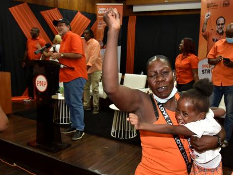 A People’s National Party delegate, with daughter in tow, cheers during party President Mark Golding’s presentation at a divisional conference held at The University of the West Indies, Mona, on Saturday.