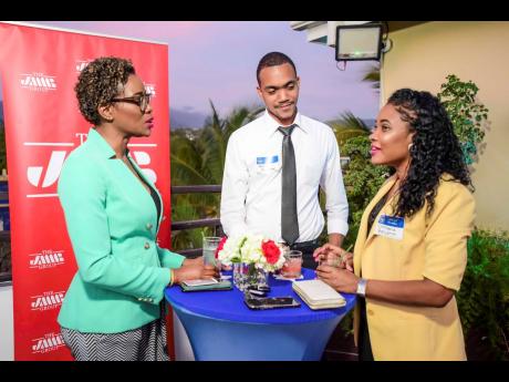 JMMB’s  Client Relationship Manager Nadine Thomas (left) and Aaron Anderson, business development manager, enjoy a light-hearted conversation with Christine Benjamin, sales and client services manager at Mayberry Investments Limited.
