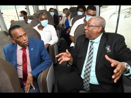 W. Billy Heaven (left), CEO of the CHASE Fund, chats with Professor Dale Webber (right), principal of The University of the West Indies, Mona, on board a bus donated to the Faculty of Medical Sciences by the CHASE Fund and Toyota Jamaica yesterday. Immedia