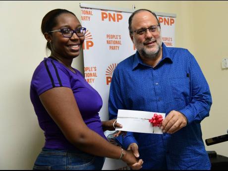 Georden Shaw (left) accepts a J$75,000 grant from People’s National Party President and Opposition Leader Mark Golding yesterday. Shaw was among the 22 Jamaican students who were forced to flee Ukraine in the wake of the Russian invasion in February 2022