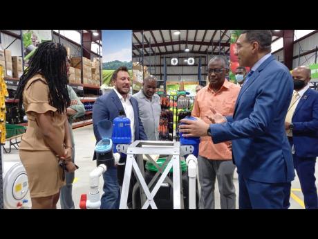 Prime Minister Andrew Holness (right) examining equipment in the Isratech Jamaica superstore with (from left) Manchester Central Member of Parliament Rhoda Crawford, CEO of Isratech, Benjie Hodara, and custos of Manchester, Garfield Green.
