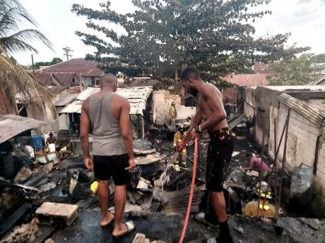 Two men from the community providing cooling-down operations after a fire left more than a dozen persons homeless in Kingston Wednesday.