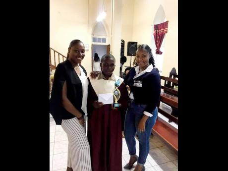 Crisann Francis (left), public relations officer, Bless to Bless Foundation and Charlene Dixon, the foundation’s founder and chief executive officer, present a book voucher and the Most Improved Award to Javel Anderson, a former student of Trinityville P
