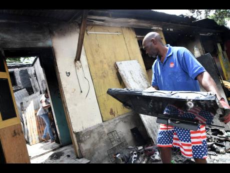 Trevor Watson carries a destroyed television set outside as he and other relatives survey losses and try to start the process of picking up the pieces following a devastating fire at their home on Thursday. They four men who lived at the Craig Town home lo