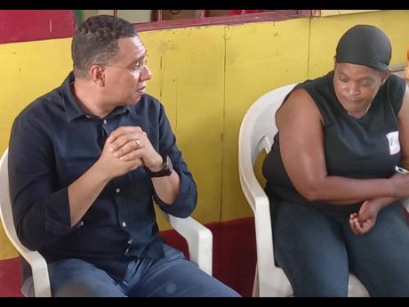 Prime Minister Andrew Holness speaking with Gwendolyn McKnight, whose daughter and four grandchildren were killed in the Clarendon massacre on June 21 in New Roads, Cocoa Piece. 