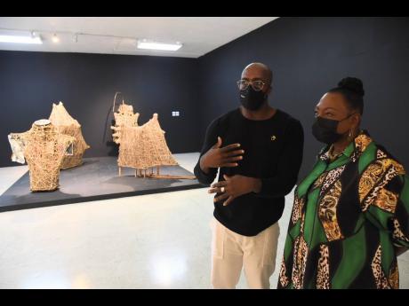 
Chief curator at the National Gallery of Jamaica, O’Neil Lawrence (left), walked Minister Olivia Grange through the exhibition. 