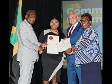 Justice Minister Delroy Chuck (second right), Bishop Conrad Pitkin, custos of St James, and Director of Public Prosecutions Paula Llewellyn (right) present the seal of Justice of the Peace (JP) to 24-year-old Roshae McKenzie, who was among 48 newly install