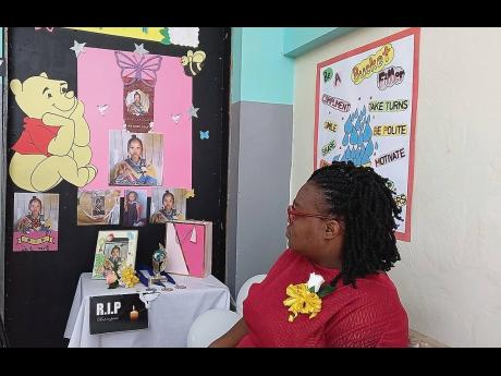 Infant teacher Tamar Blair-Robinson sits by the memorial mounted in honour of her former student, five-year-old Rafaella Smith, during the graduation ceremony at Beulah All Age and Infant School last Friday. 