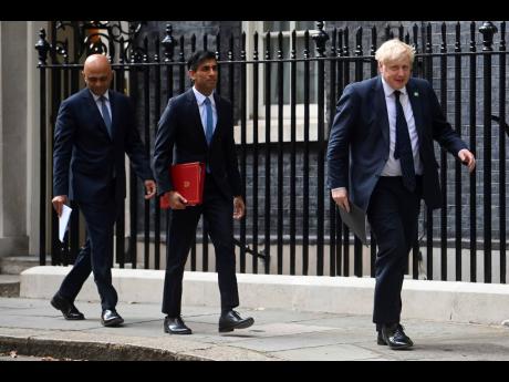 From left, British Health Secretary Sajid Javid, Chancellor of the Exchequer Rishi Sunak, and Prime Minister Boris Johnson arrive at No 9 Downing Street for a media briefing on May 7, 2021. 