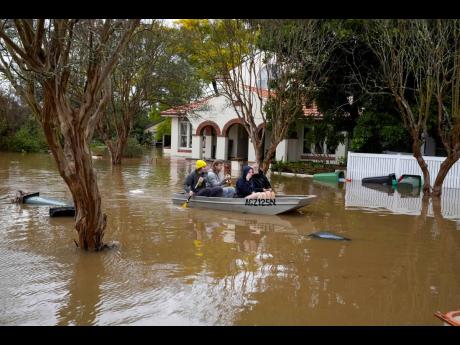 People paddle through a flooded street at Windsor on the outskirts of Sydney, Australia, on Tuesday, July 5.
