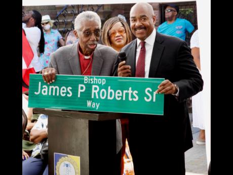 Bishop James P. Roberts Jr (left) and son William Roberts hold the street sign in honour of their late father and grandfather, respectively, at historic street co-naming ceremony in Harlem, NYC, on June 25.