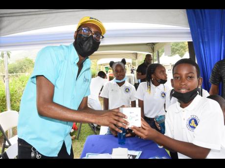 Omar Wright (left), lead, environment and community development programmes at the JN Foundation, presents a water-saving device kit to a student at Liberty Learning Centre. The occasion was the Environment and Oceans Day celebration, which was organised by