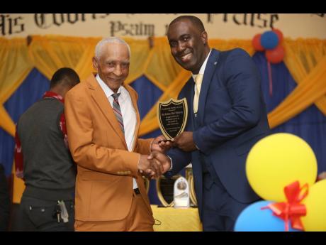 Eustace Richards (left) collects his Community Service Award from Mark Whittick of One Connection during a 10th anniversary ceremony in Crofts Hill, Clarendon, on June 25.