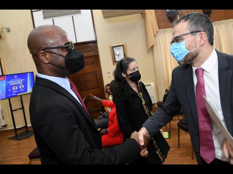 Dr Adrian Stokes (left), chairman of the Education Transformation Oversight Committee, greets Vicente Teran, deputy representative of UNICEF, at a Jamaica House press conference on Wednesday. At centre is Dr Rebecca Tortello, UNICEF education specialist.