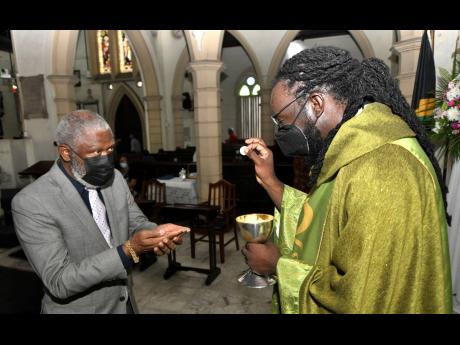 Dreadlocked priest, the Rev Bertram Gayle (right), administers communion to economist John Jackson during a service at the St Andrew Parish Church in Half-Way Tree on Sunday. Gayle was recently ordained as an Anglican priest.