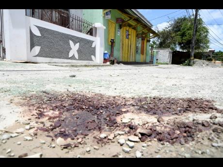 The blood-stained road where Denise Bell and her common-law spouse, Germaine Jeffrey, were attacked in Seaforth, St Thomas, on Saturday night. Both succumbed to gunshot wounds.
