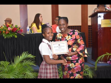 Jehelianna Dobson, valedictorian for John Rollins Success Primary School’s graduating class of 2022, receives her certificate from class teacher Olivene Green-Walker during the 18th annual school-leaving ceremony at the Montego Bay Convention Centre in R