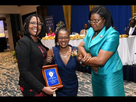 Angela McKenzie (centre), awarded for 34 year of dedicated service to education, being escorted by Kerrina Leslie (left), manager of Jamaica Publishing House, and Georgia Waugh Richards at the JTA’s Golden Torch awards ceremony at The Jamaica Pegasus hot