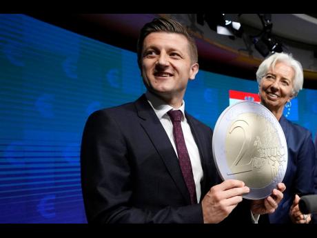 AP 
Croatia’s Finance Minister Zdravko Maric, left, holds up a cardboard euro coin as he poses with European Central Bank President Christine Lagarde after a signing ceremony for Croatia to join the euro in Brussels on Tuesday, July 12, 2022.