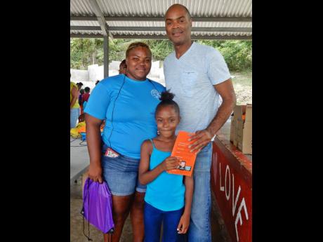 Ian Clough (right) poses for a photo with seven-year-old Exchange All-Age School student, Deshauntae Gardner, seen here holding the tablet she received, and her mother, Amanda Thomas.