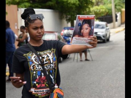 A protester on Chelsea Avenue in New Kingston displays a poster with the photograph of missing social-media influencer Donna-Lee Donaldson on Sunday. 