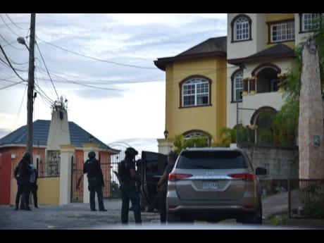 Members of the security forces standing guard outside a home in Westgate Hills, Montego Bay, St James, during simultaneous anti-narcotics operations at various locations in St James and St Andrew yesterday.