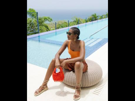 Shielding from the rays of the sun in Isle of Eden specs, Tash Ogeare wears a one-shoulder Ted Baker piece, crepe linen stretch talbot shorts by Joseph, Armani Exchange knotted lace up sandals and clutches a Mango beaded fringe bag.
