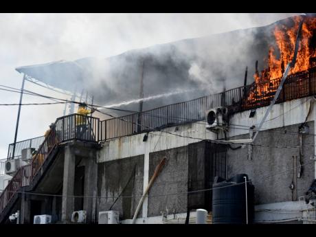 Firefighters battle a blaze at Premier Plaza in Half-Way Tree, St Andrew, yesterday. Several businesses suffered losses as a result of the fire, the cause of which is still being investigated.