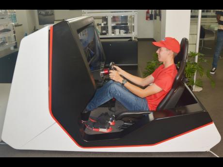 Tommi Gore gets a taste of the second stage of the 2022 Simracing World Cup using the Porsche Jamaica sim rig at the JSRA Simracing World Cup National Qualifier Awards Ceremony on July 16.  DOUBLE-CHECK ‘SIMRACING’