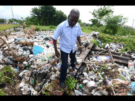 Audley Gordon, then chief technical officer of the NSWMA, walks through a pile of garbage along Industrial Terrace on September 16, 2016. Now executive director, the agency has come under scrutiny from the Auditor General’s Department.