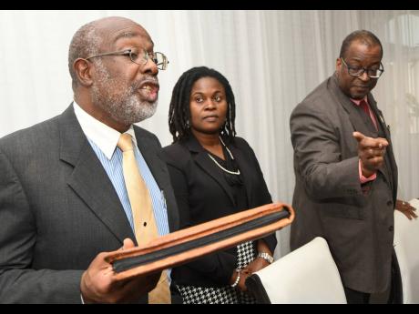 Fitz Jackson (left), MP for St Catherine Southern, addresses a press conference at Spanish Court Hotel in New Kingston on Tuesday. Also pictured are his attorneys, Anthony Williams and Annette Henry. Jackson filed a lawsuit in the Supreme Court seeking a d
