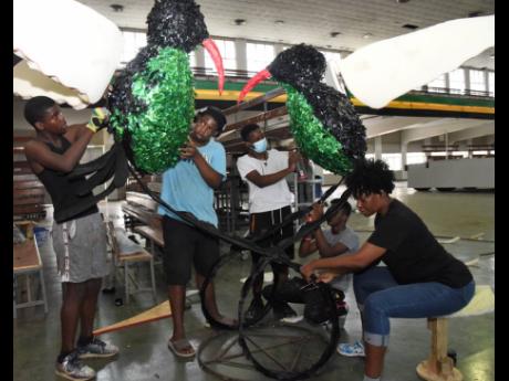 Judith Turner (right) art teacher at The Queen’s School is assisted by volunteers to create a pair of doctor birds while in preparation last Thursday for the Emancipation Day Float Parade. 