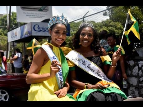 Miss Jamaica World 2021 Khalia Hall (left) and Miss Jamaica Festival Queen 2021 Dominic Reid proudly wave Jamaican flags as they make their way down Half-Way Tree Road. 