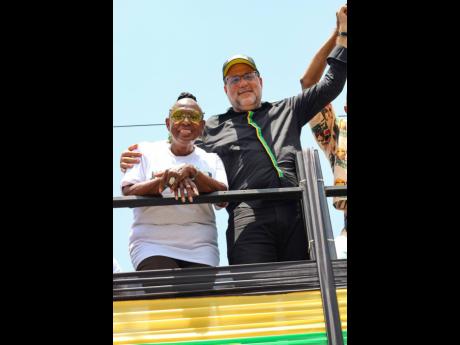Minister of Culture, Gender, Entertainment and Sport Olivia ‘Babsy’ Grange and Opposition Leader Mark Golding are observed having a laugh atop the VIP viewing deck during the Jamaica 60 Float and Street Parade.