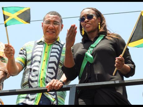Prime Minister Andrew Holness and wife Juliet Holness, member of parliament for East Rural St Andrew, flash smiles and throw kisses from one of the trucks. 