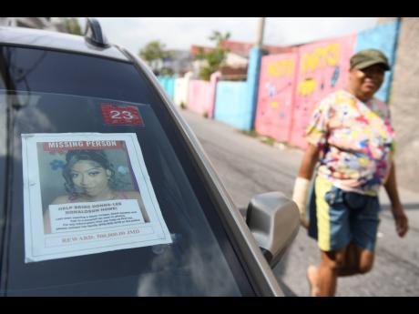 Jermadeen Lugg, the aunt of social-media influencer Donna-Lee Donaldson, walks past a car bearing the poster of the 24-year-old who went missing in mid-July. 