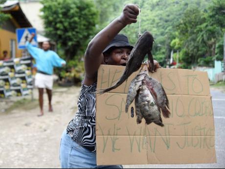 Displaying dead fish retrieved from the Rio Cobre, Joan Barrett cries for justice during a protest in Kent Village, St Catherine, on Saturday. 