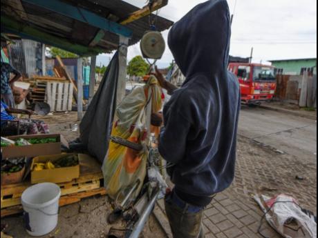 A ‘picker’ weighs metal that he salvaged from the dump in Riverton City, St Andrew, on August 6. Some residents, salvagers, and business interests have expressed opposition to Prime Minister Andrew Holness’ plan to shut down the garbage dump, arguing