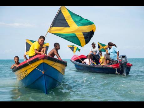 Jamaican flags blow in the wind as the Jamaica 60 boat parade thrilled spectators in Treasure Beach, St Elizabeth, on the weekend.