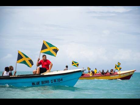 Jamaican flags blow in the wind as the Jamaica 60 boat parade thrilled spectators in Treasure Beach, St Elizabeth, on Saturday.